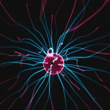 A scientific close-up photograph of a plasma globe's central electrode glowing bright red against a black background, discharging dozens of electric energy arcs and wavy filaments in vibrant cyan blue and magenta pink. This high-energy physics visual serves as a metaphor for the focused, high-powered study environment achieved by science students enrolling in a non attending school in Delhi. By selecting a legal flying admission in Delhi, medical and engineering aspirants can channel their full daily energy away from standard classroom routines and into core exam preparation, while securely retaining their high-value eligibility for the 85% Delhi state quota in NEET and the regional Delhi quota in JEE.